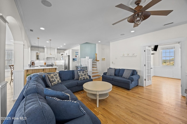 4248 Island Dr, North Topsail Beach, NC 28460 - living area featuring ceiling fan, ornamental molding, light wood-style floors, stairway, and arched walkways