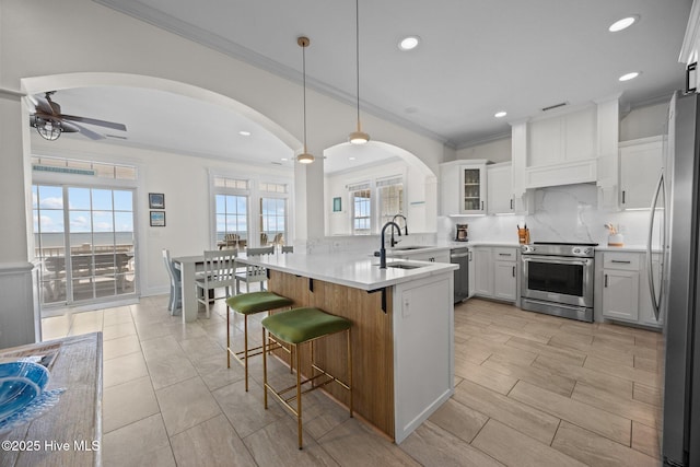 4248 Island Dr, North Topsail Beach, NC 28460 - kitchen with appliances with stainless steel finishes, a peninsula, ornamental molding, a breakfast bar, and ceiling fan