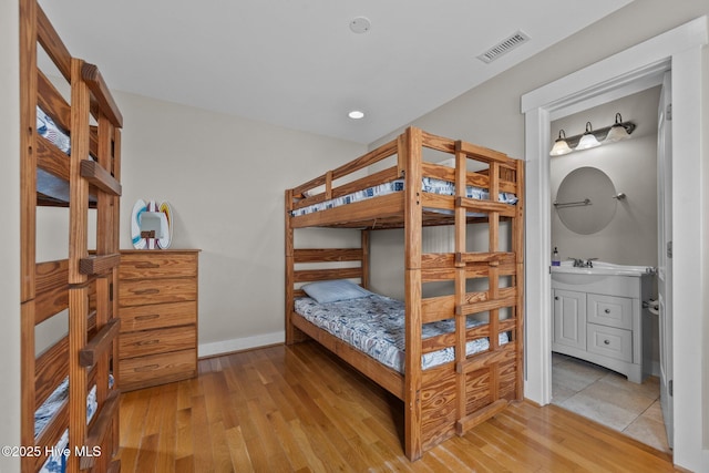 4248 Island Dr, North Topsail Beach, NC 28460 - bedroom featuring light wood-style flooring, a sink, baseboards, and connected bathroom