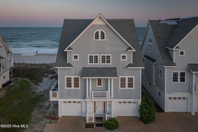 4248 Island Dr, North Topsail Beach, NC 28460 - view of front of house featuring a balcony, an attached garage, view of water and beach, concrete driveway, and a shingled roof