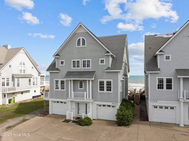 4248 Island Dr, North Topsail Beach, NC 28460 - view of front of house featuring a shingled roof, view of water and beach, an attached garage, a balcony, and driveway