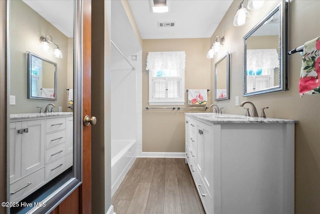 302 Mcglamery St, Oak Island, NC 28465 - full bath with double vanity, wood finished floors, baseboards, and shower / bath combination