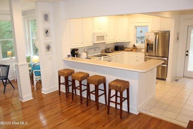 19 Sabal Palm Trl, Bald Head Island, NC 28461 - kitchen with white appliances, a breakfast bar, a peninsula, and white cabinetry