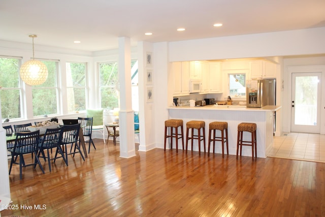 19 Sabal Palm Trl, Bald Head Island, NC 28461 - kitchen with stainless steel fridge, white microwave, hardwood / wood-style floors, a breakfast bar, and recessed lighting