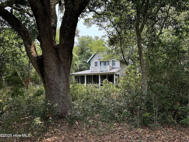 19 Sabal Palm Trl, Bald Head Island, NC 28461 - view of front of property with a sunroom, a view of trees, and a metal roof