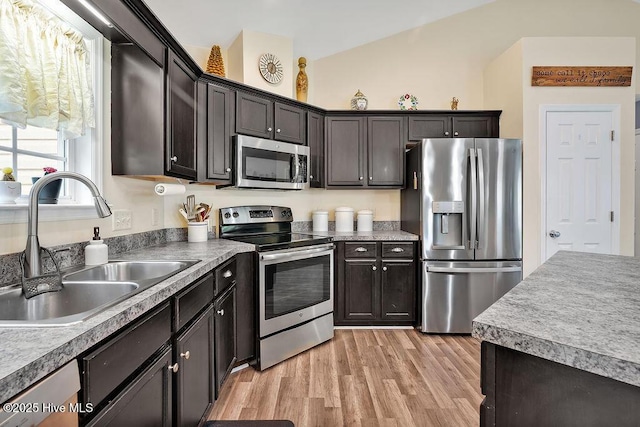 235 Chambers St, Winnabow, NC 28479 - kitchen featuring appliances with stainless steel finishes, a sink, light wood finished floors, vaulted ceiling, and dark brown cabinetry