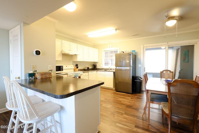 1116 E Ft Macon Rd, Atlantic Beach, NC 28512 - kitchen featuring white appliances, a peninsula, dark countertops, a sink, and wood finished floors