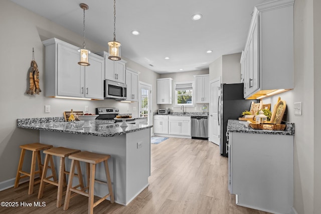 104 S 30th St, Morehead City, NC 28557 - kitchen featuring stainless steel appliances, a peninsula, a sink, dark stone counters, and recessed lighting