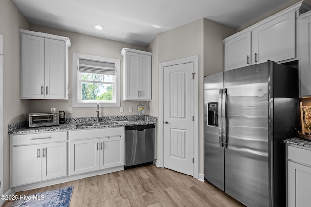 104 S 30th St, Morehead City, NC 28557 - kitchen featuring stainless steel appliances, a sink, light stone countertops, white cabinets, and light wood-style floors