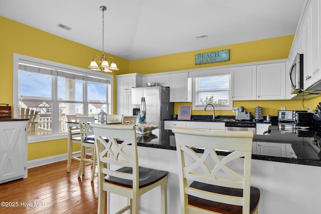 2414 Ocean Dr, Emerald Isle, NC 28594 - kitchen featuring stainless steel appliances, a chandelier, white cabinets, a sink, and pendant lighting