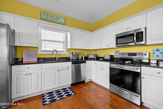 2414 Ocean Dr, Emerald Isle, NC 28594 - kitchen featuring appliances with stainless steel finishes, a sink, white cabinetry, and wood finished floors