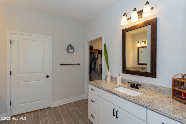 111 Pinelands Vis, Jackson Springs, NC 27281 - bathroom with vanity, baseboards, wood finish floors, and a walk in closet