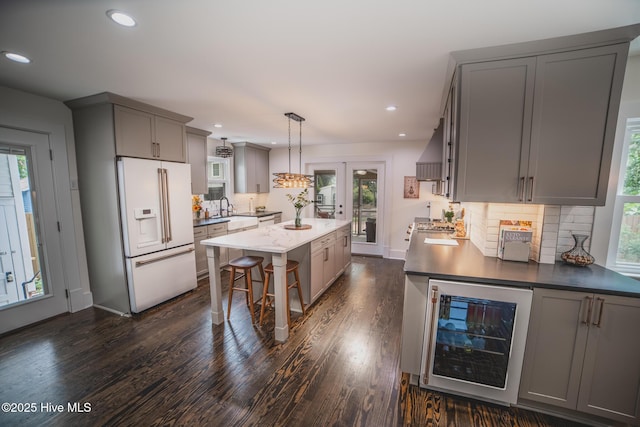 1309 N Pasteur St, New Bern, NC 28560 - kitchen featuring white fridge with ice dispenser, gray cabinets, wine cooler, a kitchen island, and tasteful backsplash