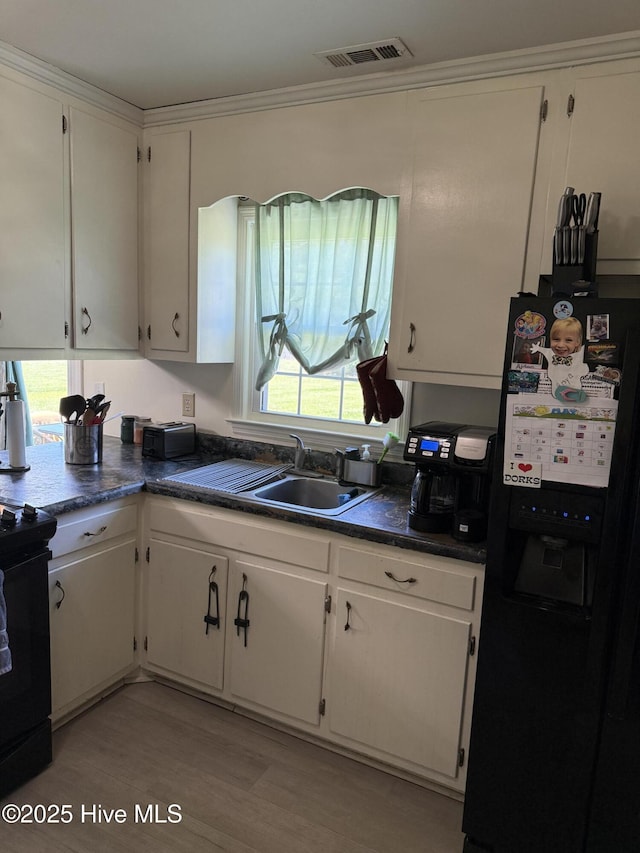 1164 Hibbs Rd, Newport, NC 28570 - kitchen with black appliances, a sink, white cabinets, dark countertops, and light wood-type flooring