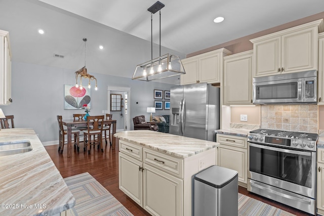 124 NE 35th St, Oak Island, NC 28465 - kitchen featuring appliances with stainless steel finishes, dark wood-type flooring, tasteful backsplash, hanging light fixtures, and light stone countertops