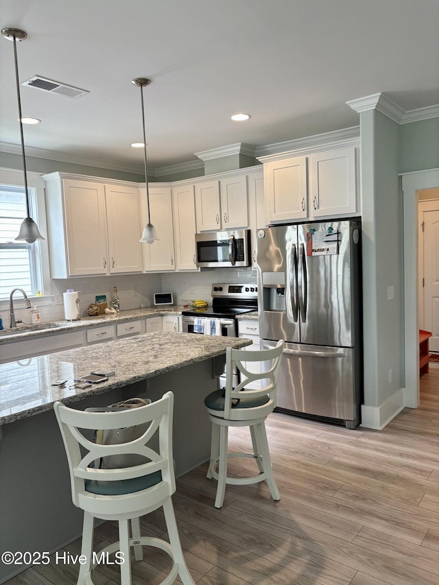 7000 Sevilleen Dr SW, Ocean Isle Beach, NC 28469 - kitchen with appliances with stainless steel finishes, a sink, ornamental molding, white cabinets, and light stone counters