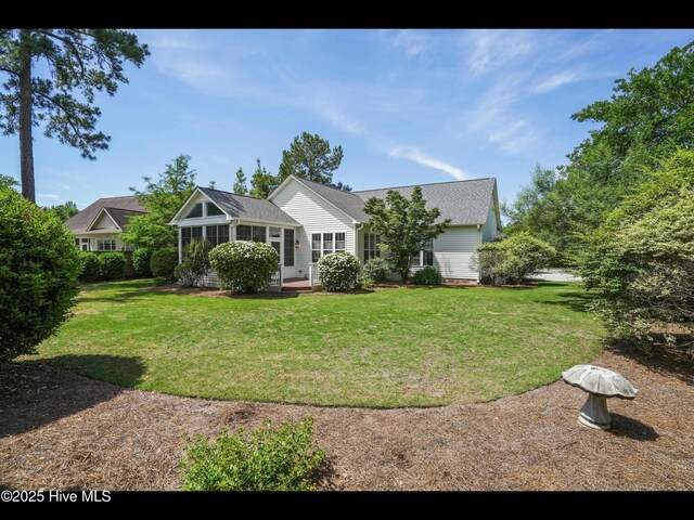 1133 Grandiflora Dr, Leland, NC 28451 - ranch-style home featuring a sunroom, a front lawn, and roof with shingles