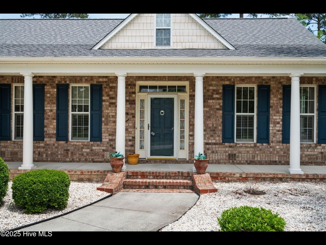 1133 Grandiflora Dr, Leland, NC 28451 - view of exterior entry featuring a porch, roof with shingles, and brick siding