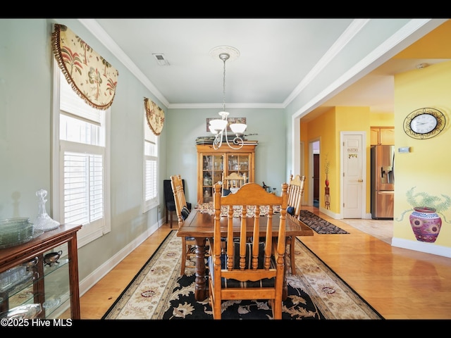 1133 Grandiflora Dr, Leland, NC 28451 - dining area with a chandelier, light wood-style flooring, crown molding, and baseboards