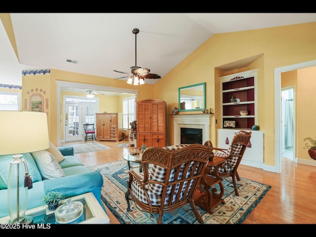 1133 Grandiflora Dr, Leland, NC 28451 - living area featuring a tile fireplace, light wood-style floors, a ceiling fan, lofted ceiling, and baseboards
