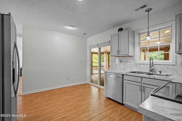 100 Hedingham Ct, Wilmington, NC 28412 - kitchen featuring appliances with stainless steel finishes, a sink, gray cabinets, light wood-type flooring, and backsplash
