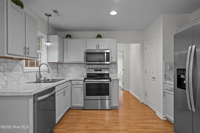 100 Hedingham Ct, Wilmington, NC 28412 - kitchen with appliances with stainless steel finishes, a sink, light countertops, light wood-style flooring, and decorative backsplash