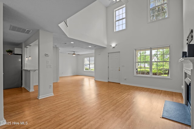100 Hedingham Ct, Wilmington, NC 28412 - unfurnished living room with ceiling fan, a fireplace with flush hearth, baseboards, light wood-type flooring, and a high ceiling