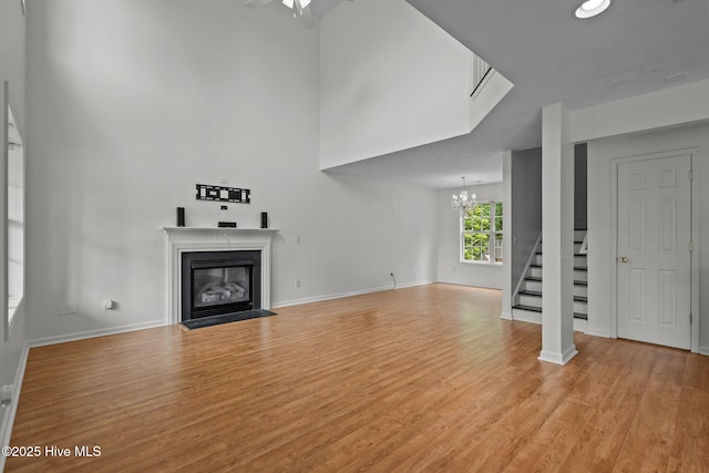 100 Hedingham Ct, Wilmington, NC 28412 - unfurnished living room with a fireplace with flush hearth, light wood-type flooring, a chandelier, stairs, and baseboards