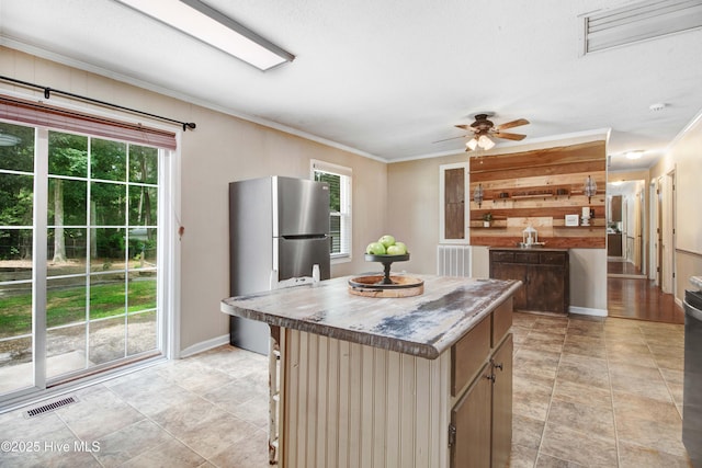 287 Perkins Rd, Goldsboro, NC 27530 - kitchen featuring freestanding refrigerator, a center island, a ceiling fan, crown molding, and a kitchen breakfast bar
