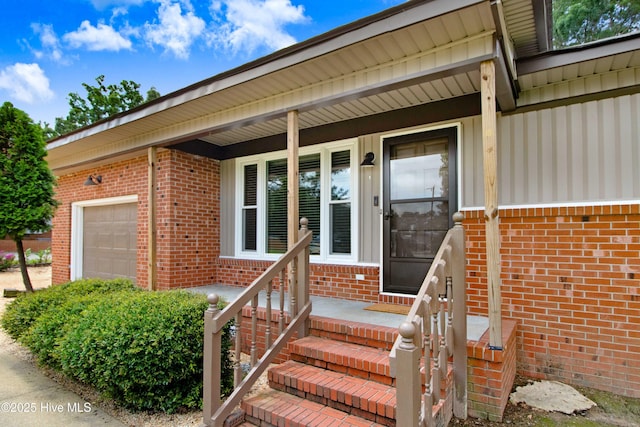 287 Perkins Rd, Goldsboro, NC 27530 - view of exterior entry featuring brick siding, an attached garage, a porch, and board and batten siding