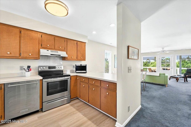 256 Brunswick Ave W Unit A, Holden Beach, NC 28462 - kitchen with appliances with stainless steel finishes, under cabinet range hood, brown cabinets, light countertops, and plenty of natural light
