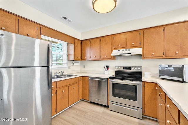 256 Brunswick Ave W Unit A, Holden Beach, NC 28462 - kitchen with stainless steel appliances, under cabinet range hood, a sink, light wood-style flooring, and light countertops