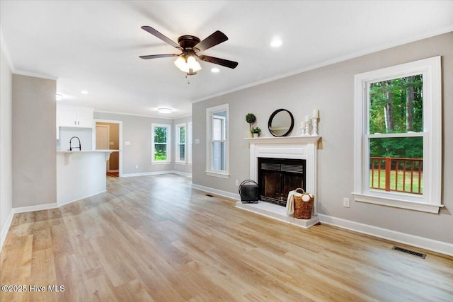 103 Sawgrass Pl, Goldsboro, NC 27534 - unfurnished living room featuring crown molding, a fireplace with raised hearth, light wood finished floors, a ceiling fan, and recessed lighting