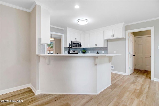 103 Sawgrass Pl, Goldsboro, NC 27534 - kitchen featuring stainless steel microwave, light countertops, a breakfast bar, white cabinets, and crown molding