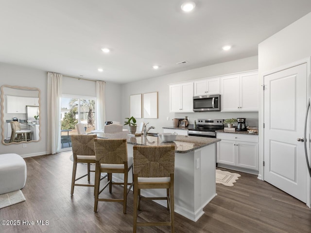 159 Legare St Lot 250, Wilmington, NC 28411 - kitchen with stainless steel appliances, a kitchen island with sink, dark stone counters, a kitchen breakfast bar, and white cabinetry