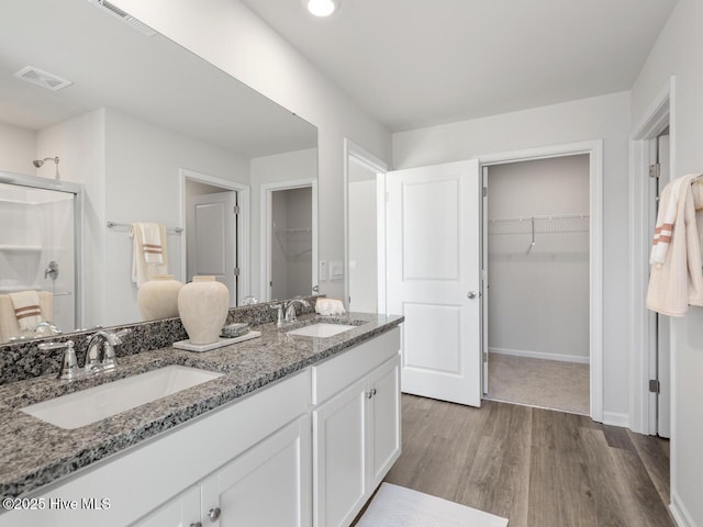 159 Legare St Lot 250, Wilmington, NC 28411 - bathroom featuring wood finished floors, a shower stall, double vanity, a walk in closet, and baseboards