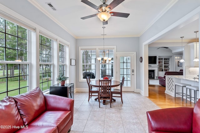 3059 Irwin Dr SE, Southport, NC 28461 - dining room featuring ceiling fan, a fireplace with raised hearth, light tile patterned flooring, a chandelier, and ornamental molding