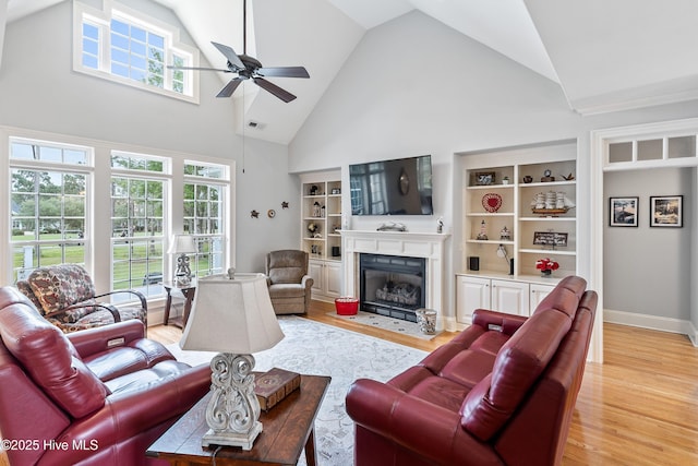 3059 Irwin Dr SE, Southport, NC 28461 - living room with high vaulted ceiling, ceiling fan, a fireplace with flush hearth, light wood-style floors, and baseboards