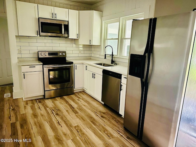 1200 N Center St, Goldsboro, NC 27530 - kitchen featuring stainless steel appliances, a sink, white cabinetry, light countertops, and ornamental molding