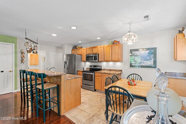 3350 Club Villas Dr # 1403, Southport, NC 28461 - kitchen with stainless steel appliances, a chandelier, a kitchen bar, light stone counters, and recessed lighting