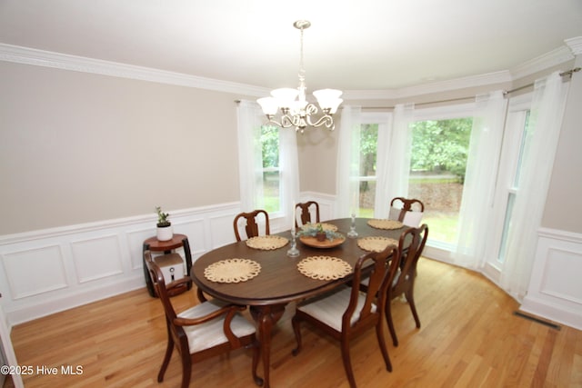 1317 Worthington Ln, Greenville, NC 27858 - dining space featuring a decorative wall, light wood-style floors, a chandelier, a wainscoted wall, and crown molding