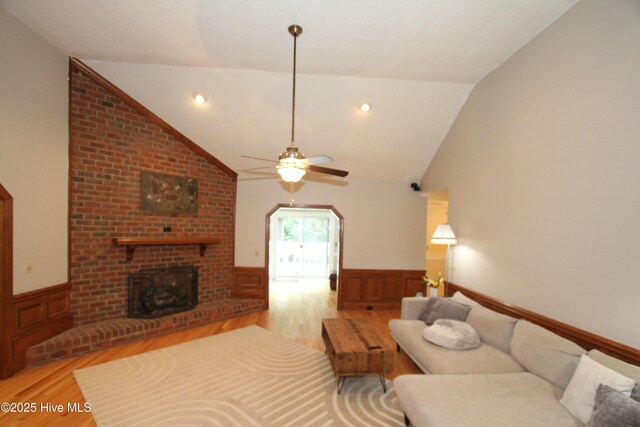 1317 Worthington Ln, Greenville, NC 27858 - living room with light wood-type flooring, vaulted ceiling, a wainscoted wall, a ceiling fan, and a brick fireplace