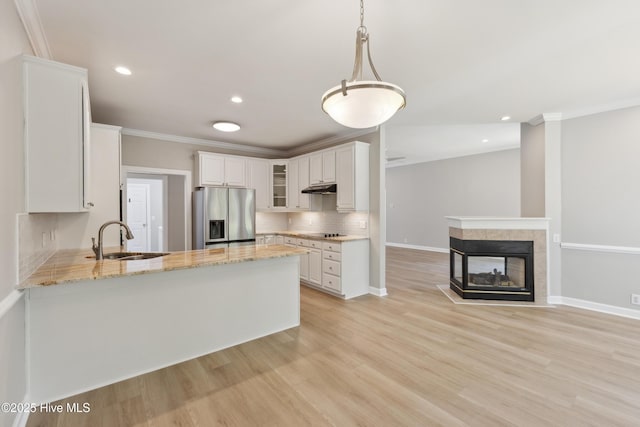 8807 Sawmill Creek Ln, Wilmington, NC 28411 - kitchen featuring stainless steel refrigerator with ice dispenser, a sink, crown molding, glass insert cabinets, and a peninsula