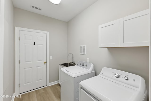 8807 Sawmill Creek Ln, Wilmington, NC 28411 - washroom featuring independent washer and dryer, cabinet space, light wood-style flooring, and baseboards