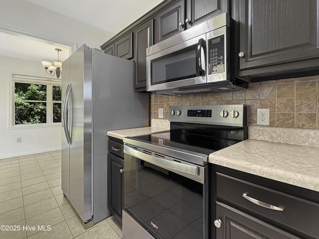 130 Summerfield St, Elizabeth City, NC 27909 - kitchen featuring appliances with stainless steel finishes, a chandelier, light countertops, light tile patterned flooring, and backsplash
