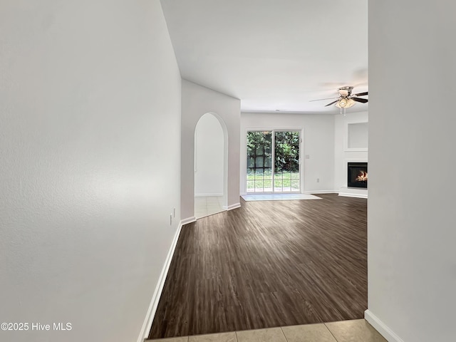 130 Summerfield St, Elizabeth City, NC 27909 - unfurnished living room with a ceiling fan, baseboards, a lit fireplace, wood finished floors, and arched walkways