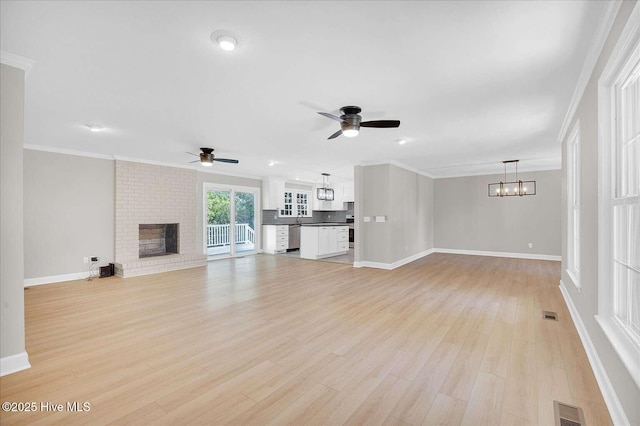 3417 Chalmers Dr, Wilmington, NC 28409 - unfurnished living room featuring ceiling fan, a chandelier, baseboards, light wood-type flooring, and a brick fireplace