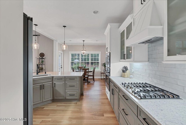 42 Spearhead Dr, Whispering Pines, NC 28327 - kitchen with premium range hood, stainless steel gas cooktop, gray cabinetry, and light wood finished floors