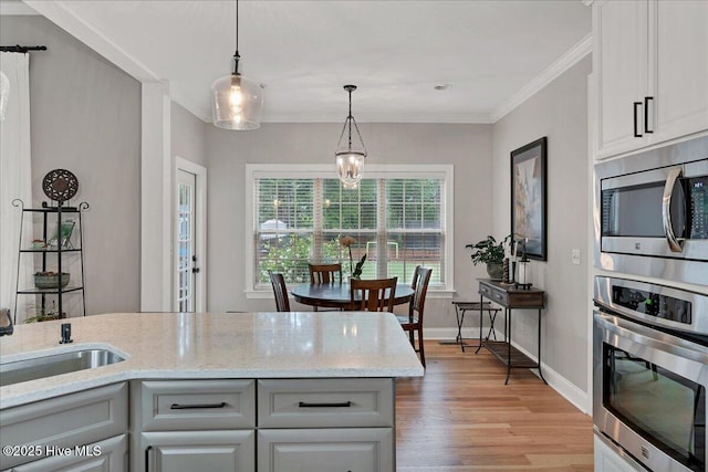 42 Spearhead Dr, Whispering Pines, NC 28327 - kitchen featuring stainless steel appliances, light wood-style floors, light stone countertops, hanging light fixtures, and baseboards