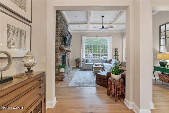 42 Spearhead Dr, Whispering Pines, NC 28327 - living room featuring light wood-style flooring, ornamental molding, ceiling fan, beam ceiling, and a stone fireplace